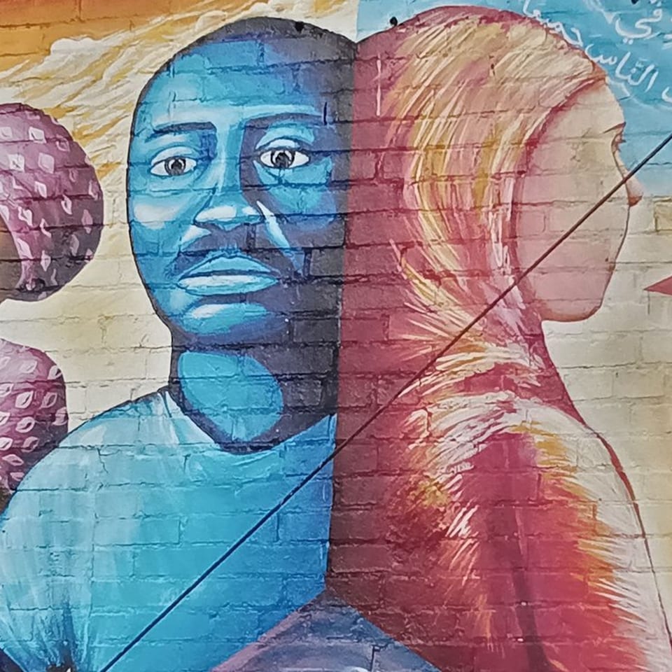 Mural of a blue-skinned man facing forward and a red-skinned woman in profile, divided by a diagonal line.