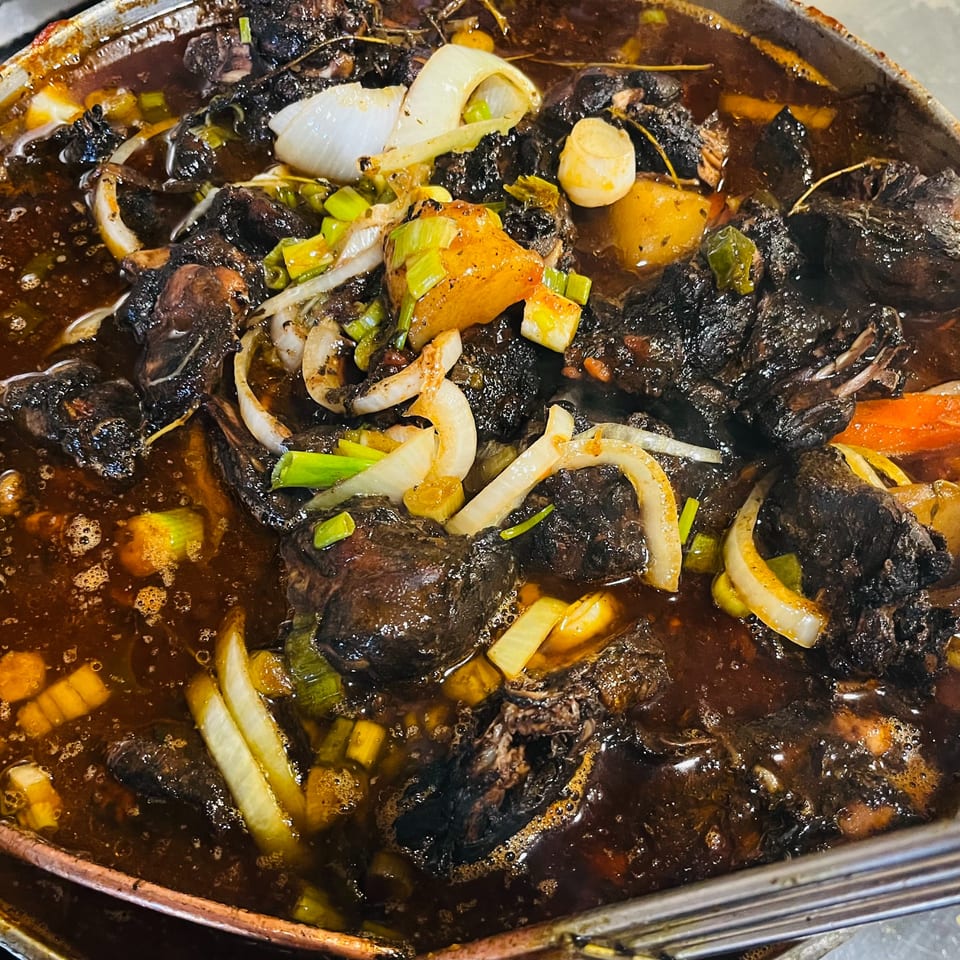 Close-up of Jamaican jerk stew with dark meat, onions, and potatoes simmering in a rich sauce.
