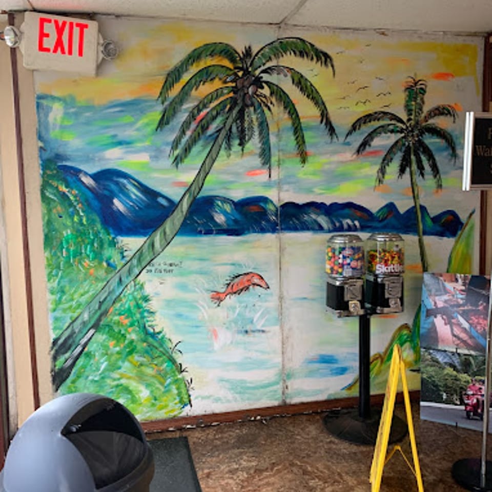 A vibrant Jamaican-themed mural with palm trees, a jumping fish, and a gumball machine.